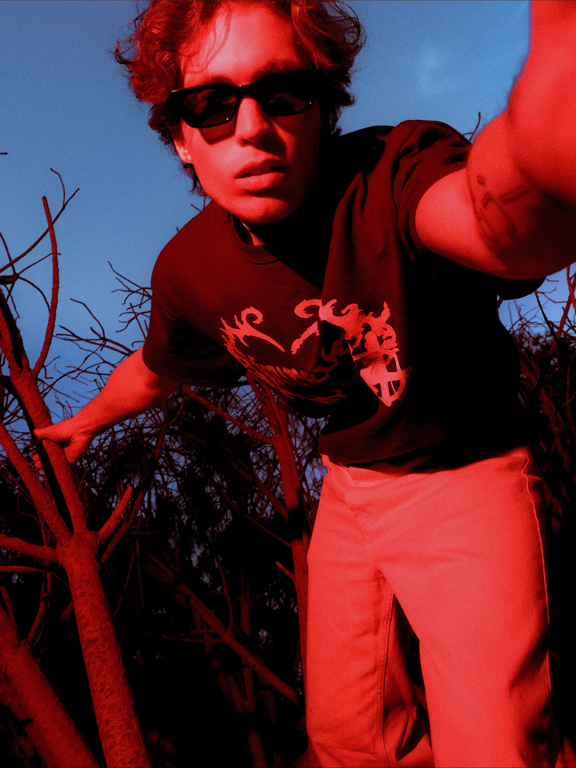 Close low angle in red light, model reaching toward the camera