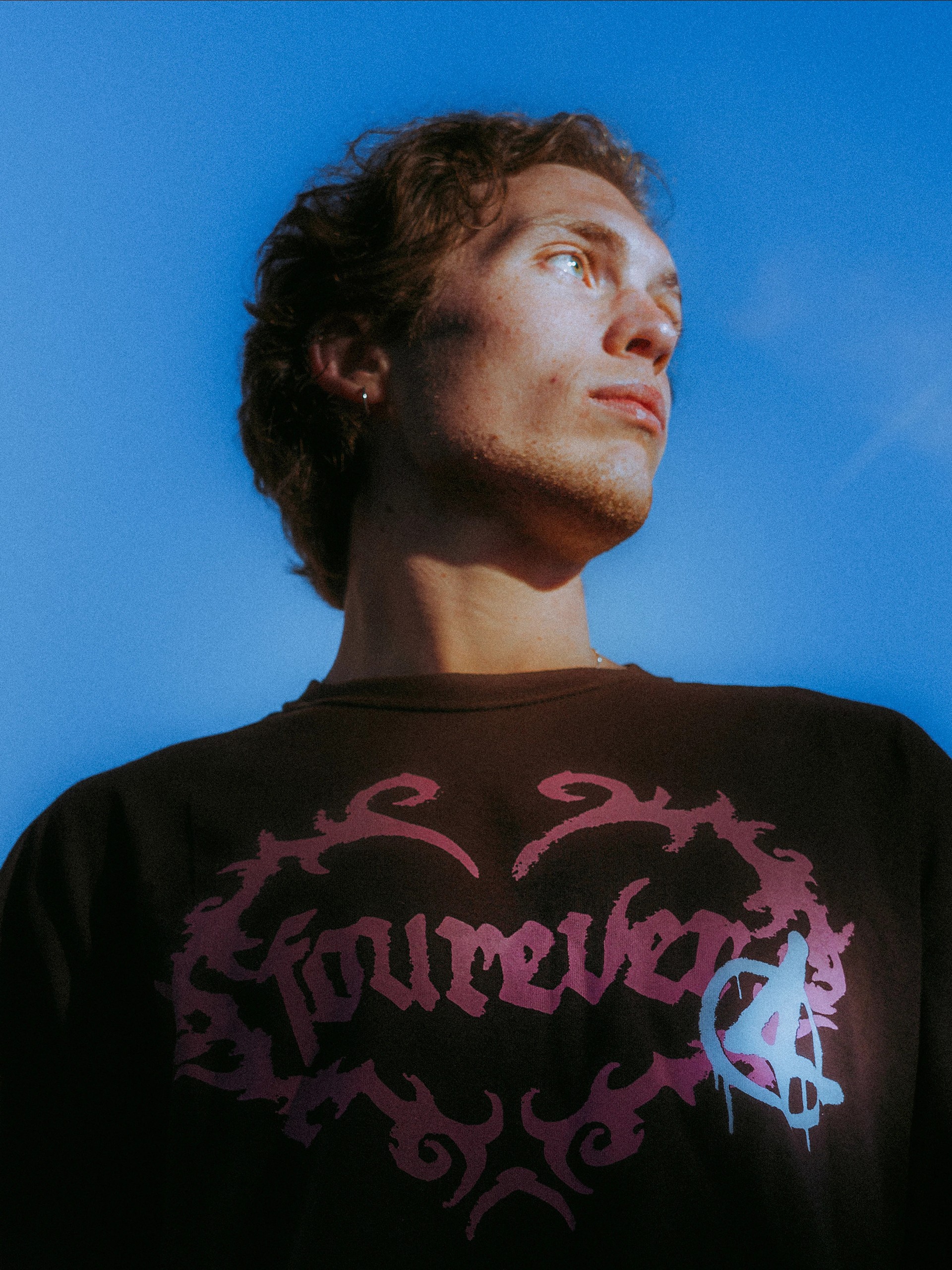 Low angle against blue sky, pink fourever graphic across the black tee