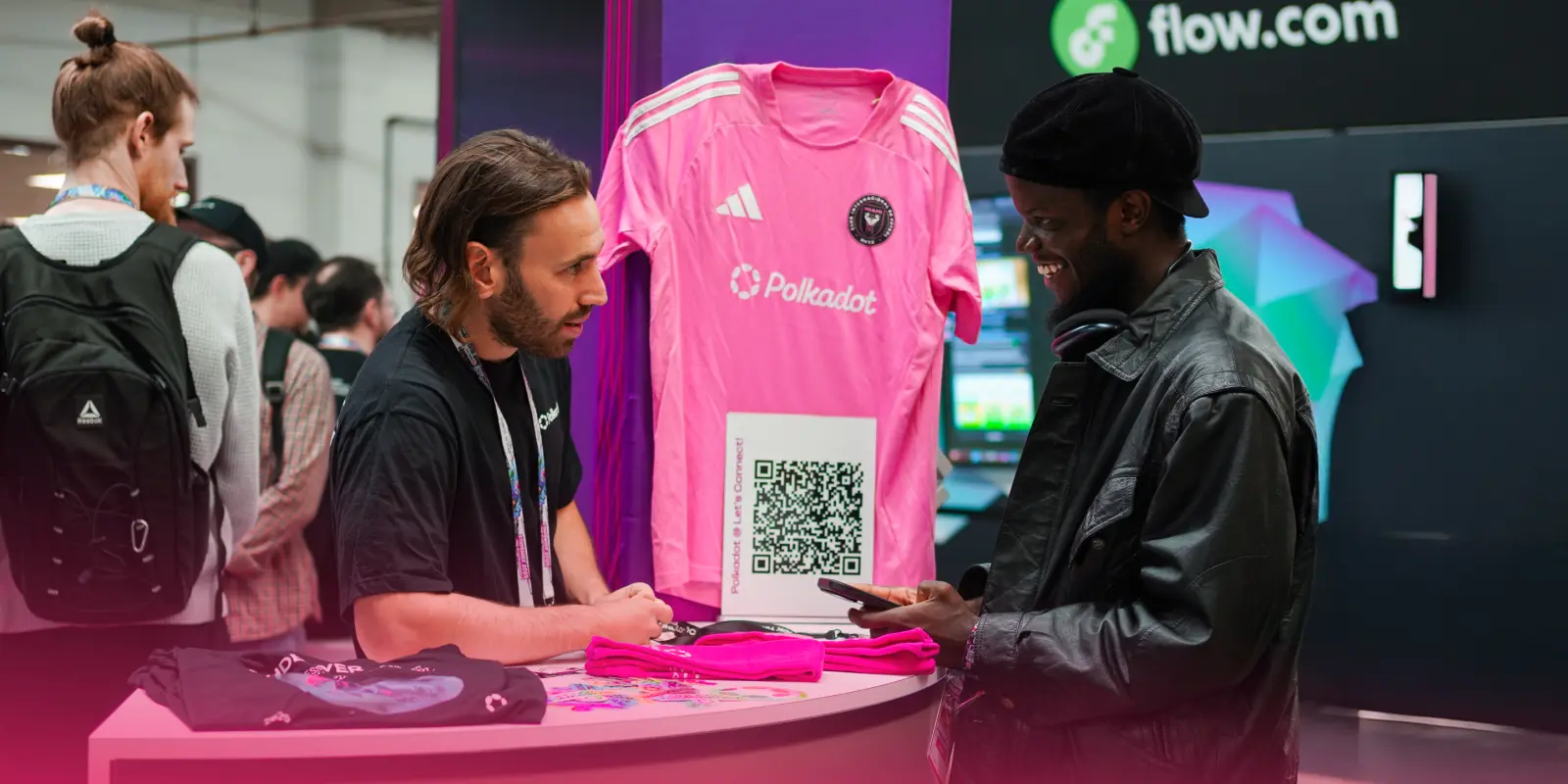 ETHDenver attendees interacting at the Polkadot booth, exploring blockchain solutions, scanning QR codes, and checking out exclusive Polkadot merchandise.