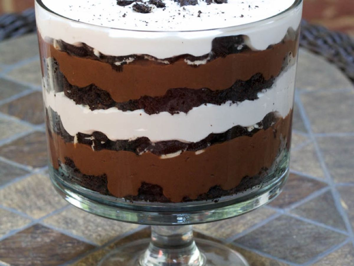 A trifle bowl layered with brownies, chocolate pudding, Oreos, and whipped topping