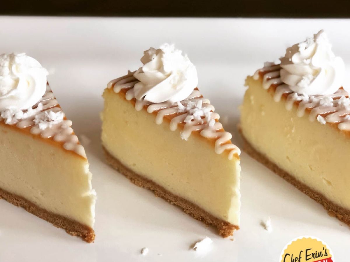 A slice of pina colada cheesecake topped with whipped cream and coconut