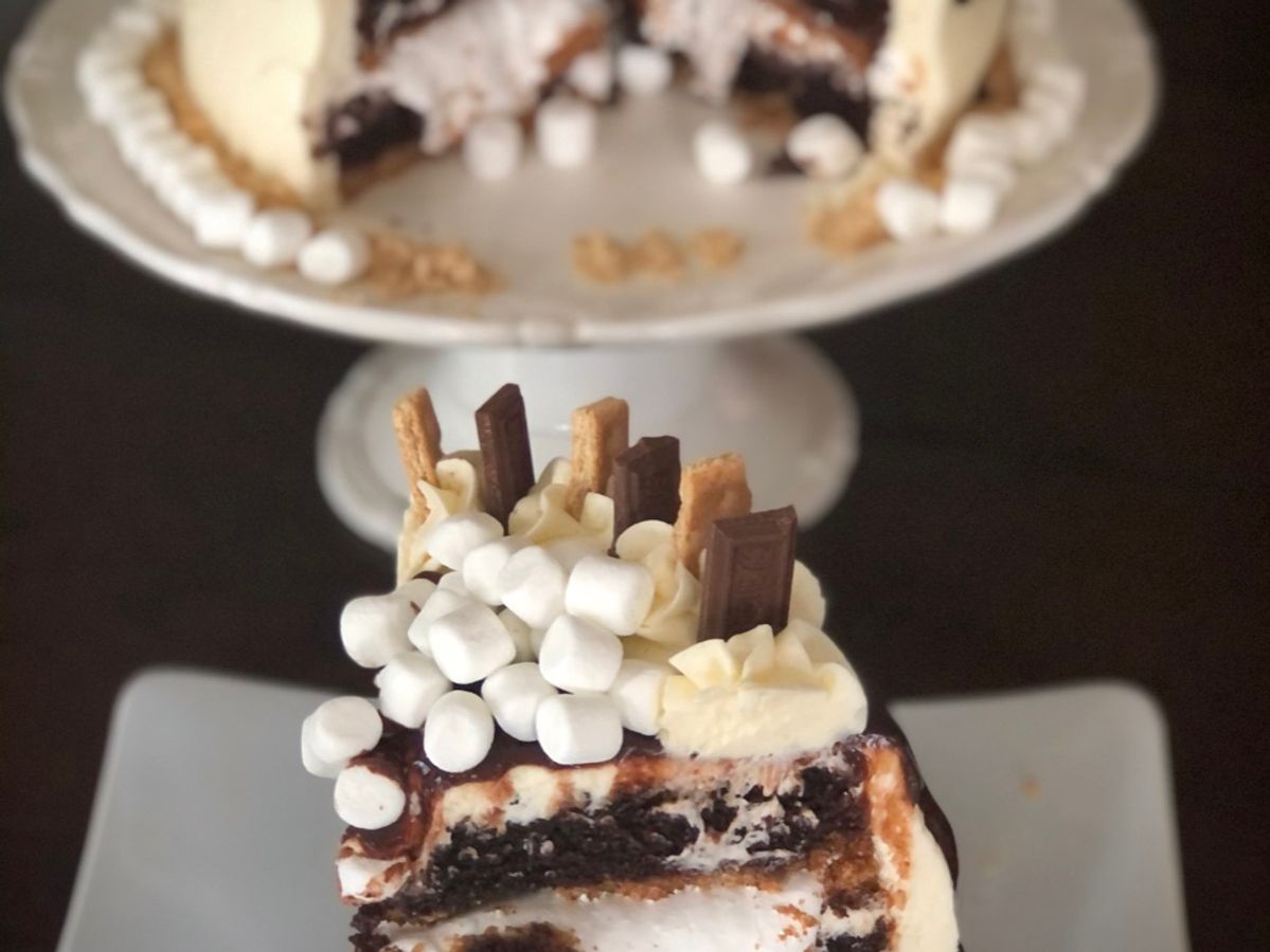 A three-layer s'mores cake covered in chocolate ganache and marshmallows