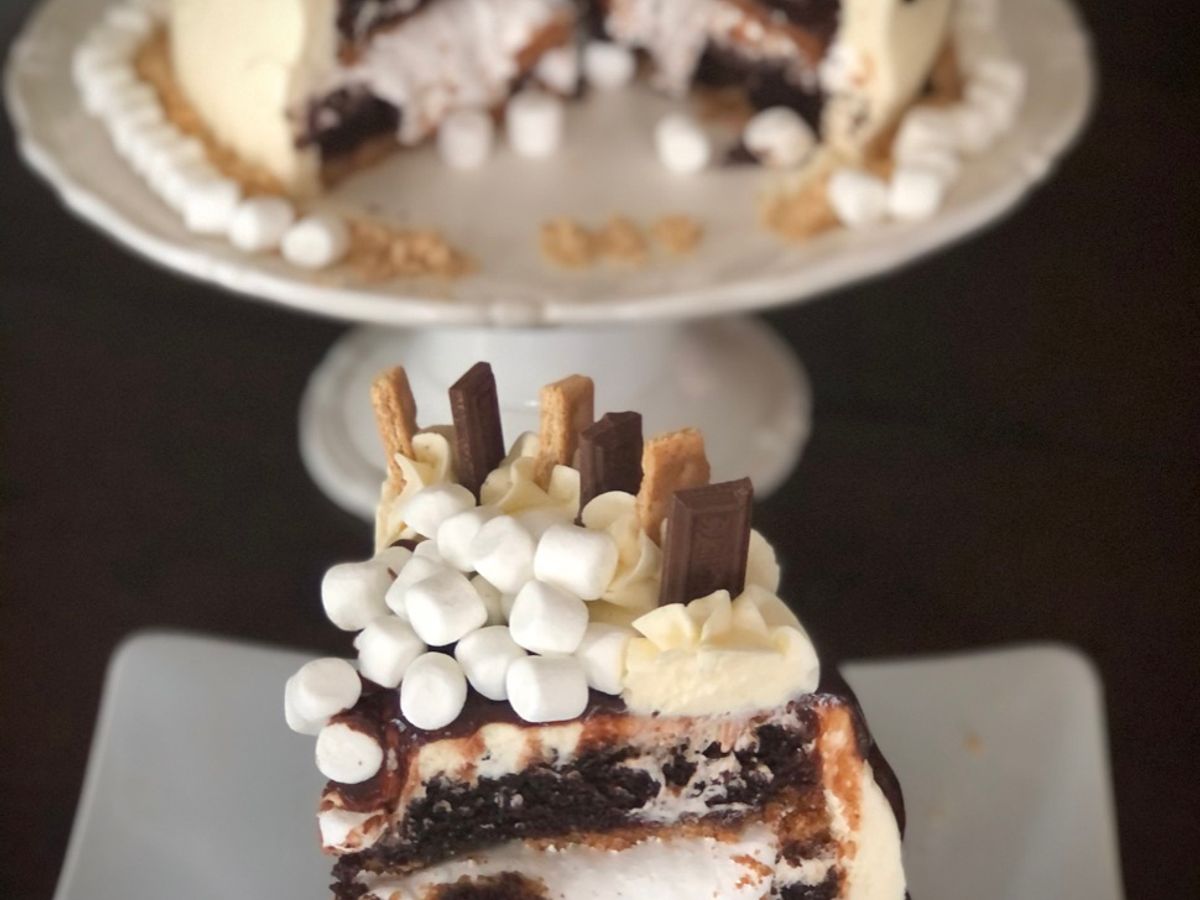 A three-layer s'mores cake covered in chocolate ganache and marshmallows