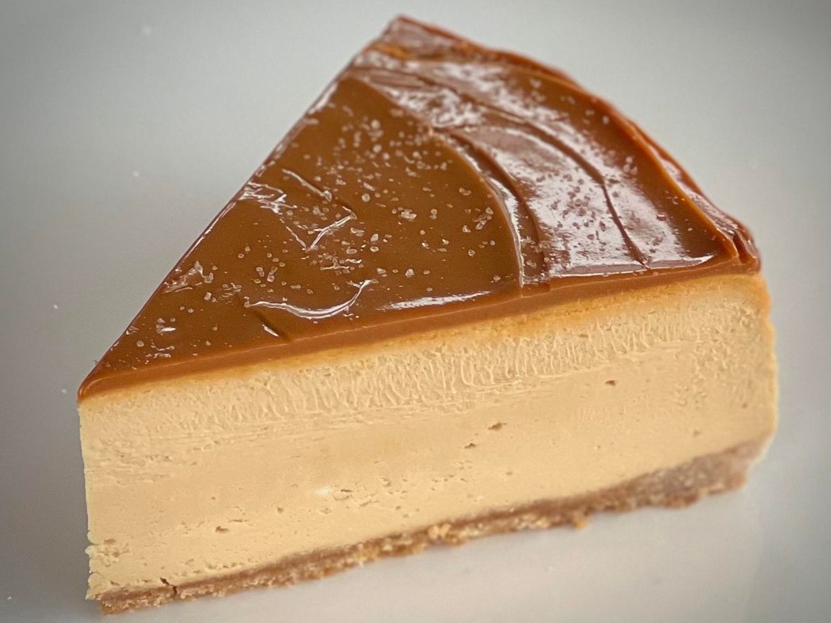 A slice of dulce de leche cheesecake topped with caramel and sea salt