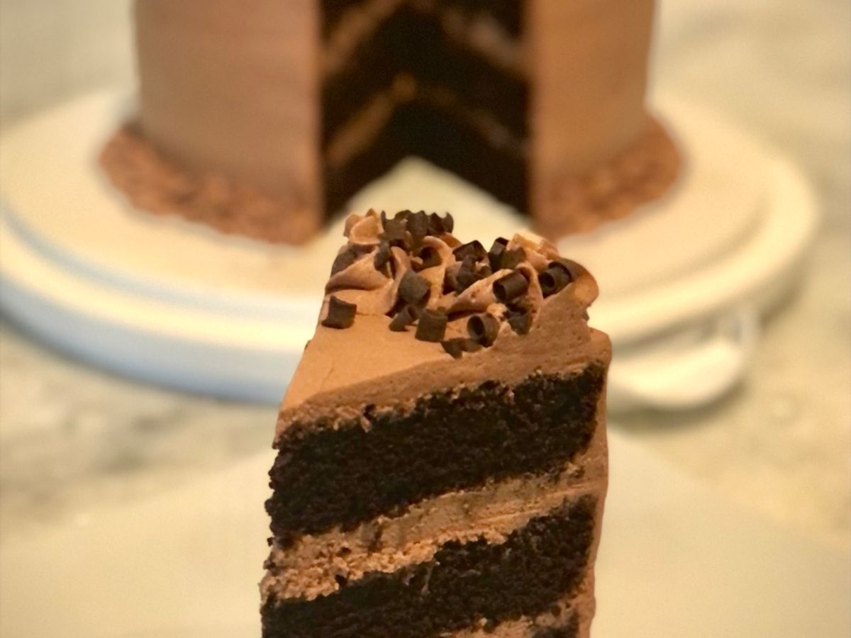 A layer cake covered in chocolate mousse icing and chocolate curls