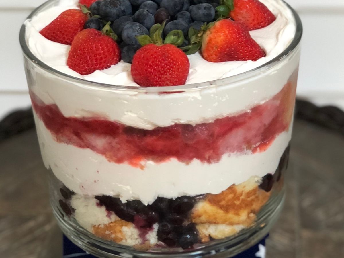A trifle dish layered with angel food cake, berries, and whipped topping