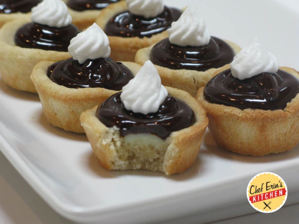 Mini Boston creme tarts topped with chocolate ganache and whipped cream
