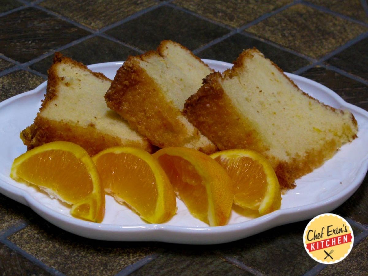 An orange chiffon cake drizzled with orange glaze on a cake stand