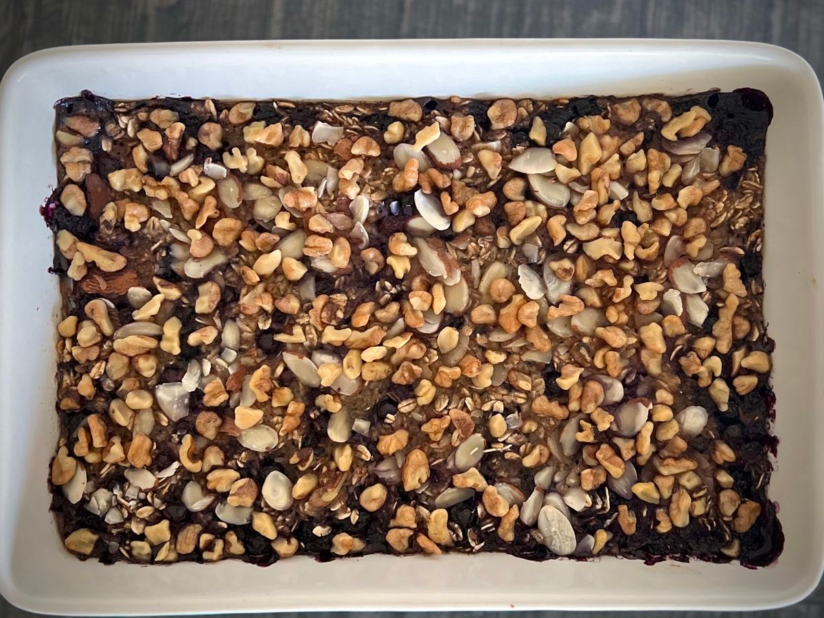 A baking dish of baked oatmeal studded with blueberries and nuts