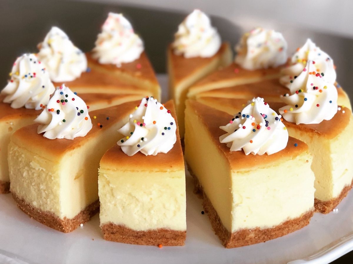 A slice of birthday cake flavored cheesecake topped with frosting and sprinkles