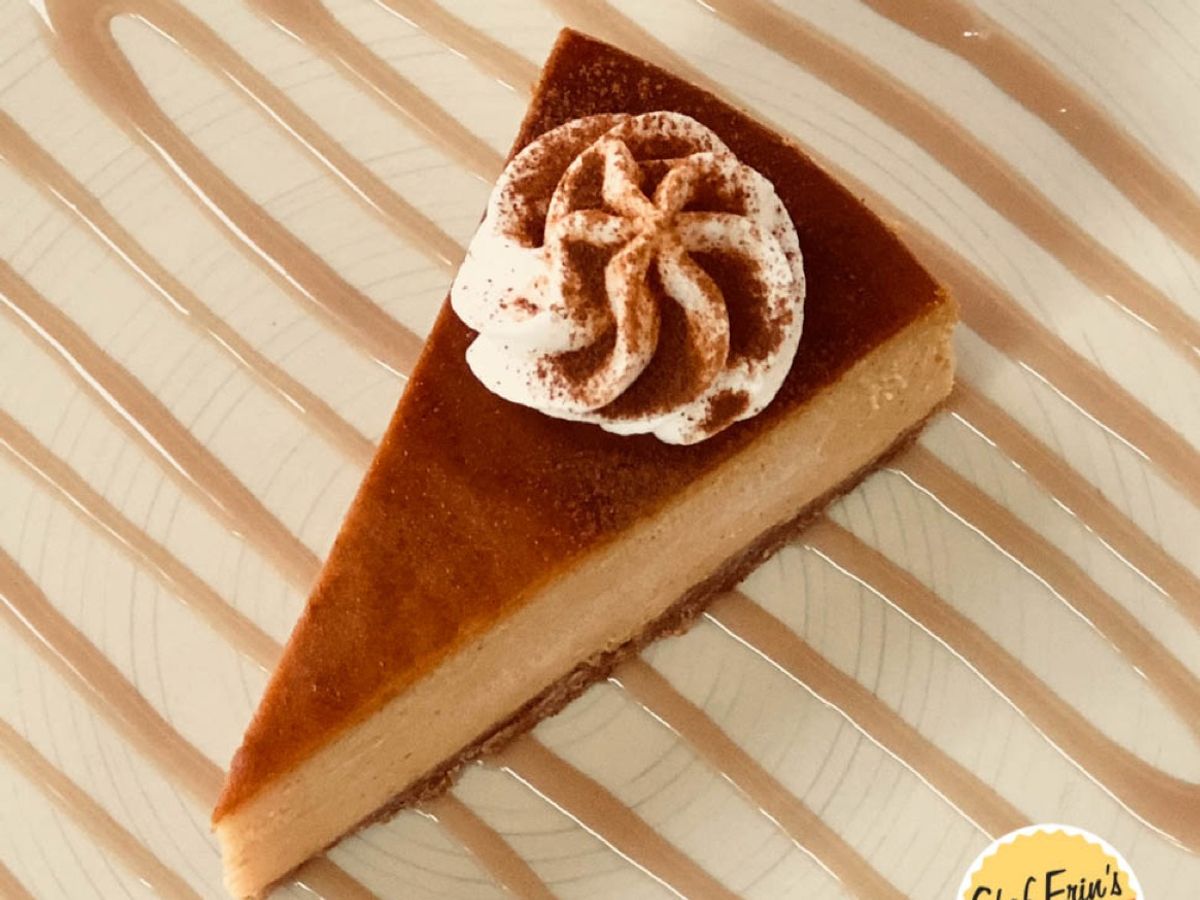 A slice of pumpkin cheesecake topped with whipped cream and caramel drizzle
