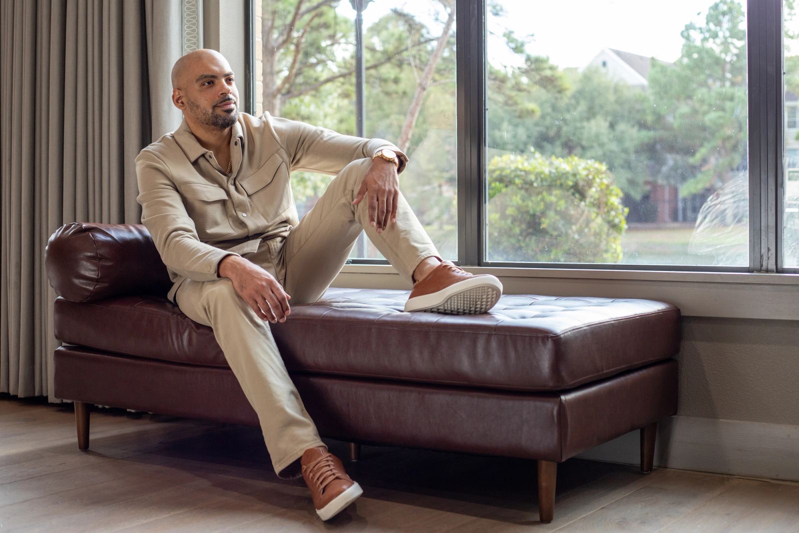 Man seated on a leather sofa by a window