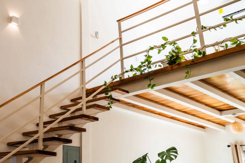 Open timber staircase rising to the mezzanine under the beamed ceiling