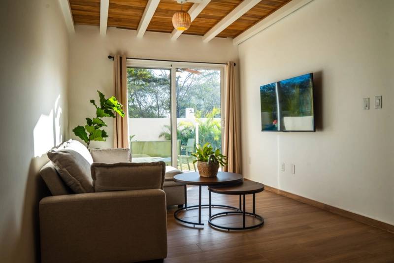 Living area with a sofa, low tables and a wall-mounted television
