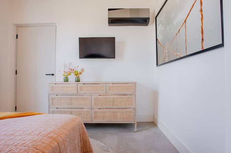 Bedroom with a rattan chest of drawers and wall-mounted television