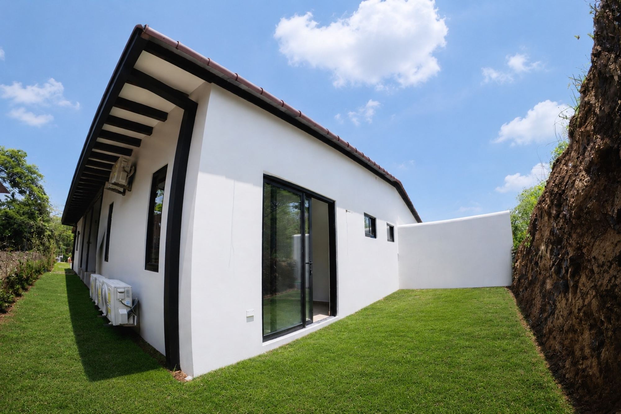 The house from outside: a long single-storey volume with black-framed windows on a walled lot