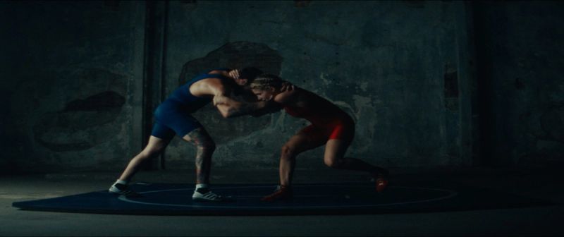Olympic wrestler Helen Maroulis grappling with an opponent on a blue wrestling mat.