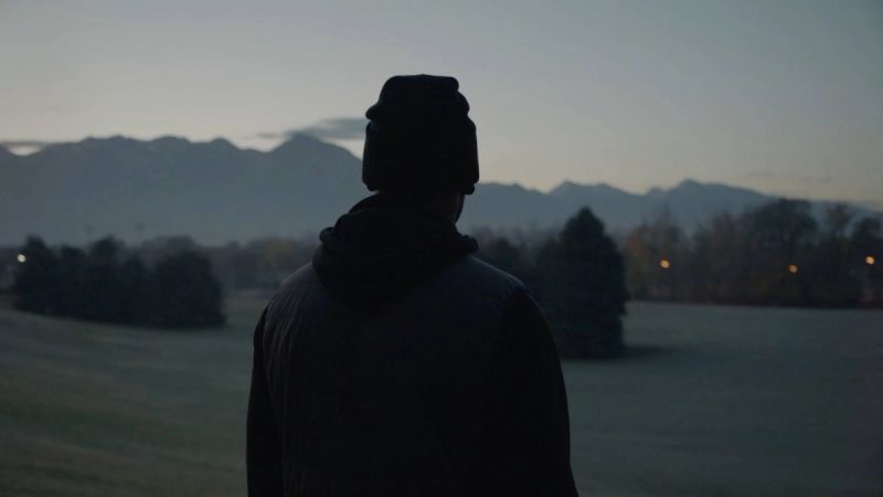 Silhouette of a person in winter gear overlooking mountains at dusk