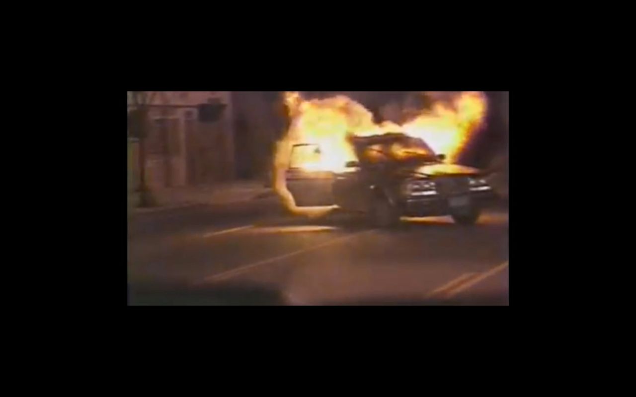 Burning car on a dimly lit street at night