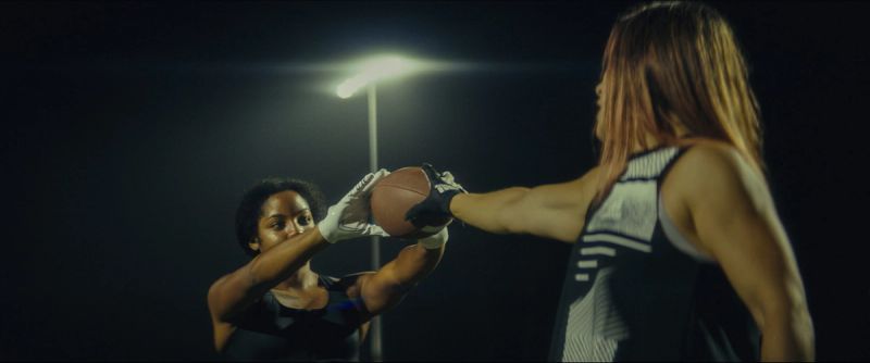 Two female athletes compete for a basketball under night lighting