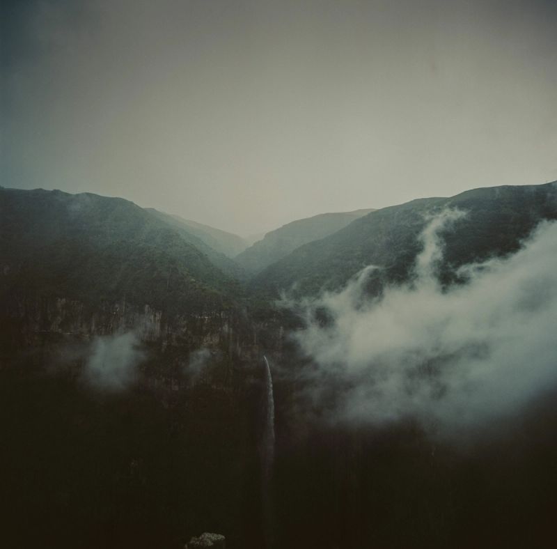 Lufthansa Airlines cinematography of a misty mountain gorge with clouds and waterfall.