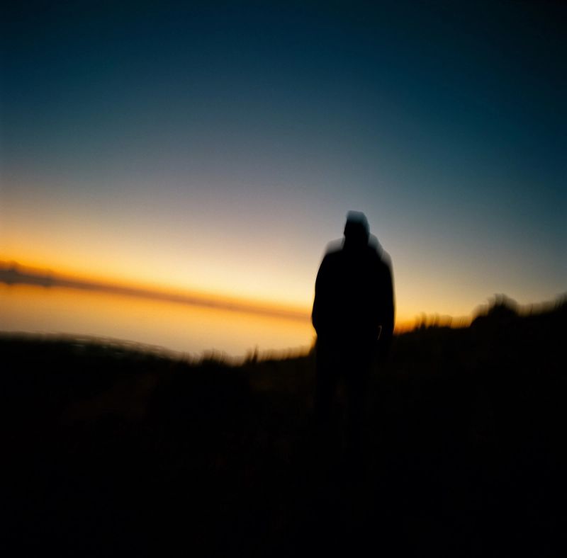 Silhouette of a person against a sunset sky over a landscape.