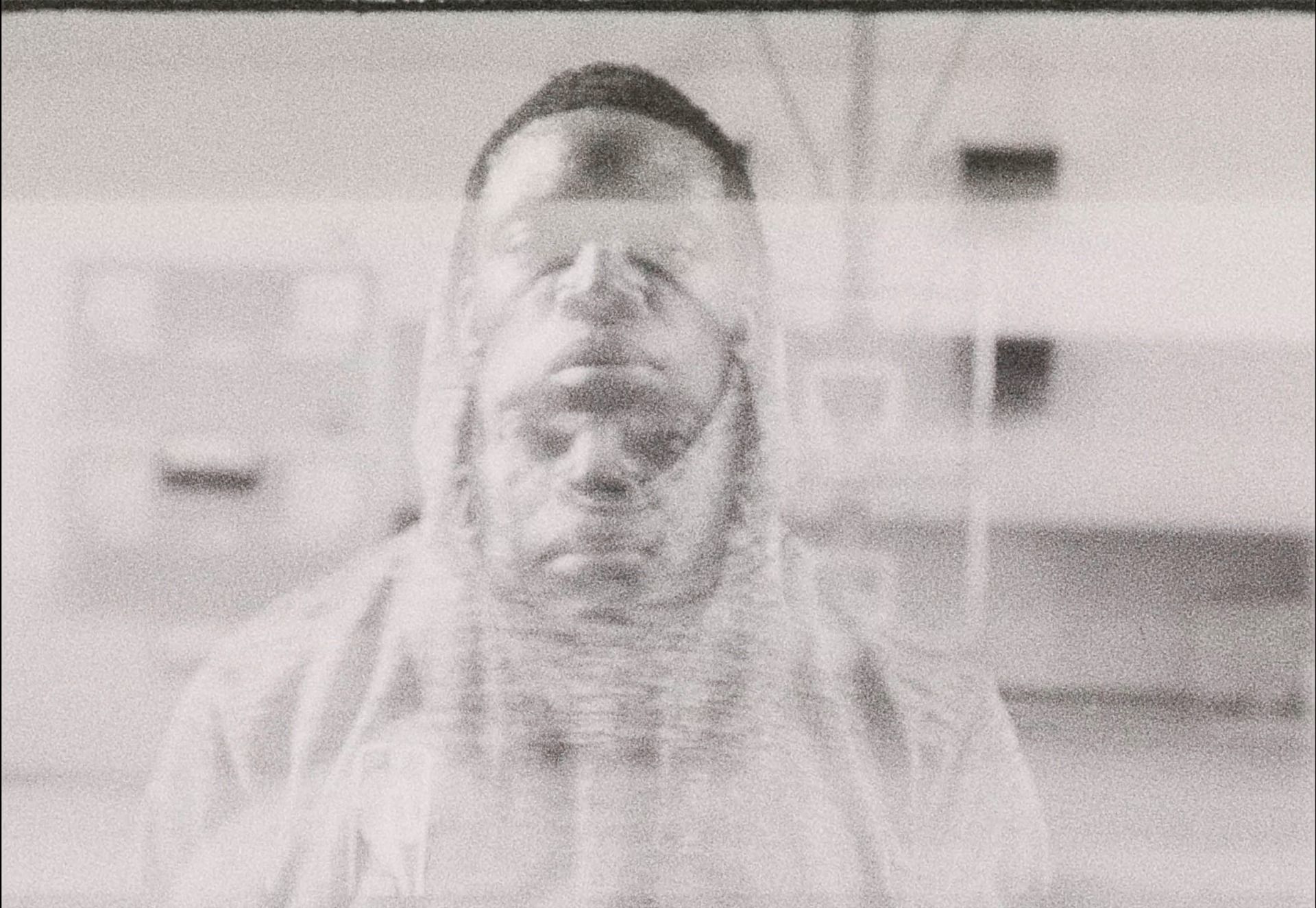 Reggie Jackson gazing through a window pane in grainy black and white film photography.