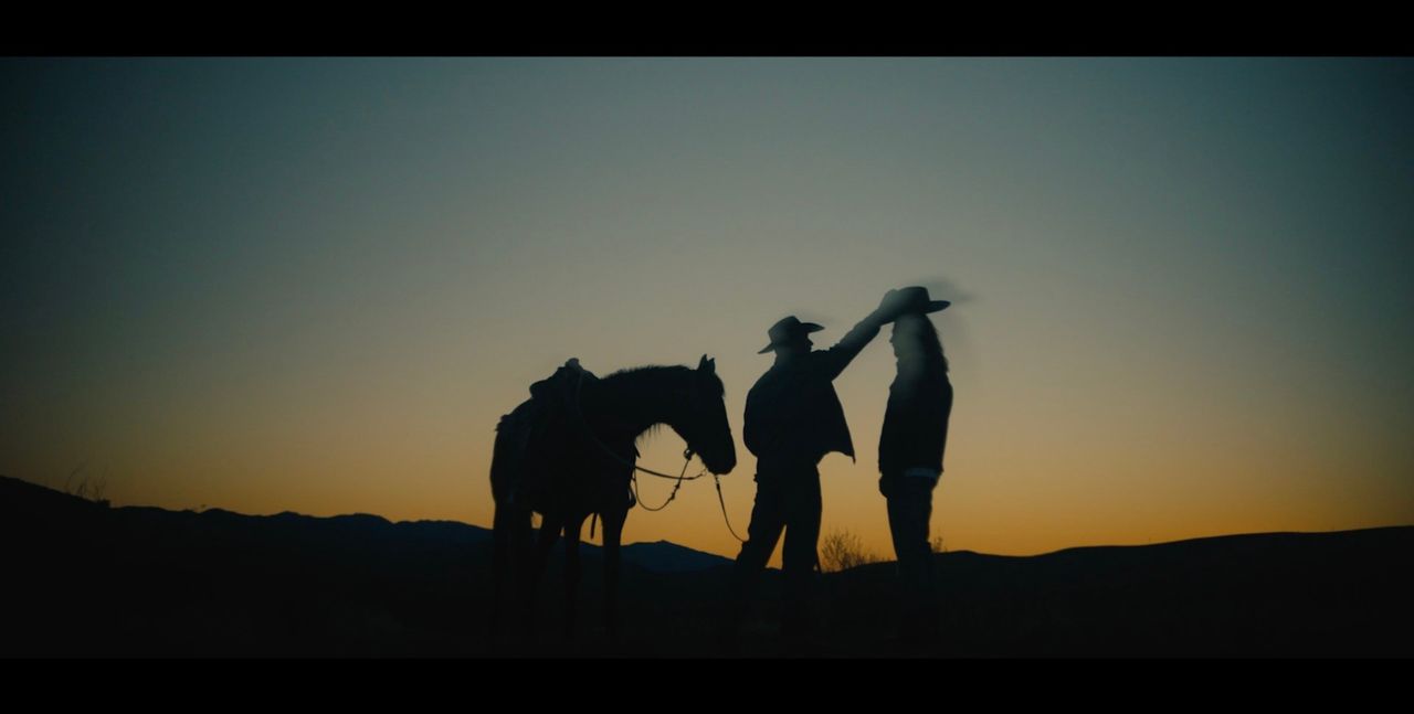 Silhouetted figures tipping hats beside a horse against a twilight sky, Mercedes Benz Marco Polo.
