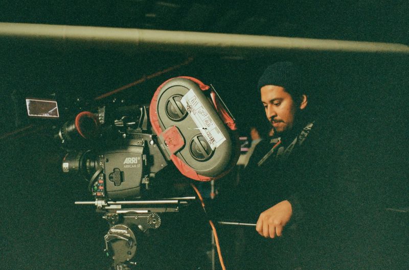 Cinematographer operating ARRI camera on film set in dimly lit environment
