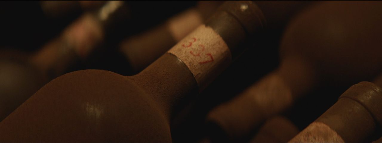 Close-up of wine bottles with handwritten labels in dim lighting