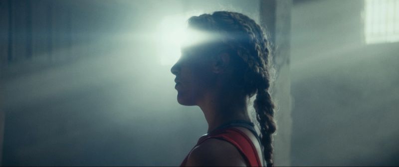 Profile of Olympic wrestler Helen Maroulis in red singlet with dramatic backlighting from a window.