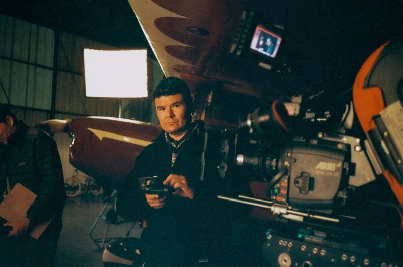 Ian Rigby operating ARRI camera on film set with vintage aircraft in background