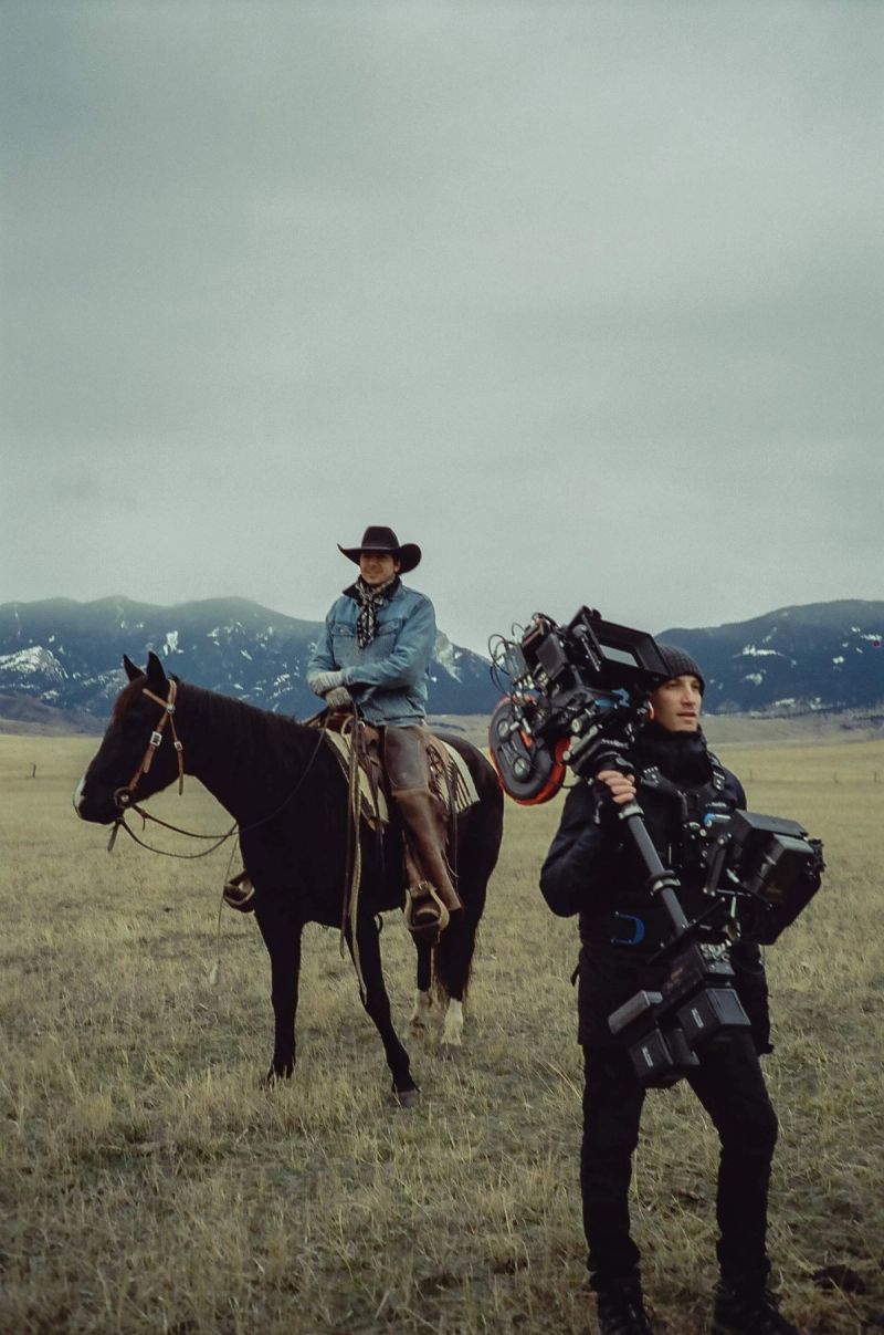 Cinematographer with Steadicam filming actor on horseback in mountainous landscape