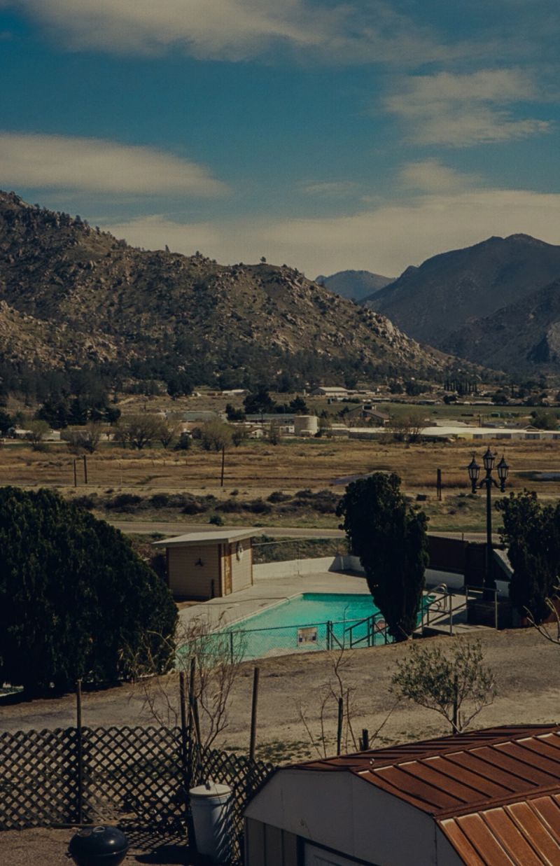 Pool and small building nestled in mountainous landscape under blue sky