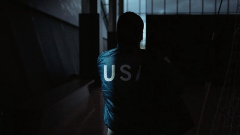 Silhouette of athlete wearing USA jacket in dimly lit indoor space