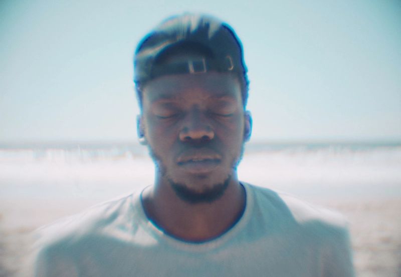 Portrait of Reggie Jackson eyes closed on a sunny beach with ocean waves.