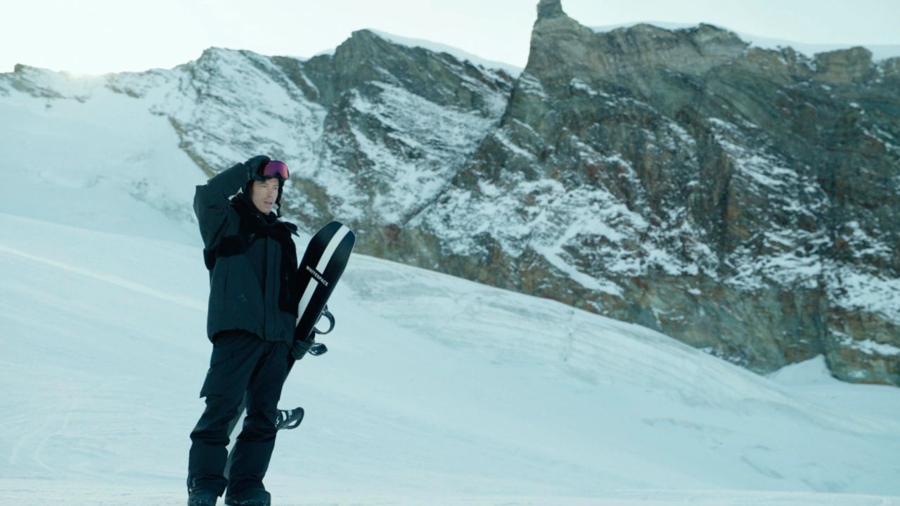 Shaun White holding snowboard in snowy mountain landscape