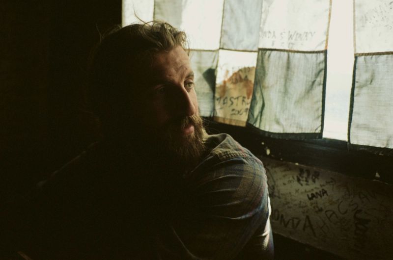 Portrait of director Trevor Paperny in shadow looking toward a window with patched fabric.