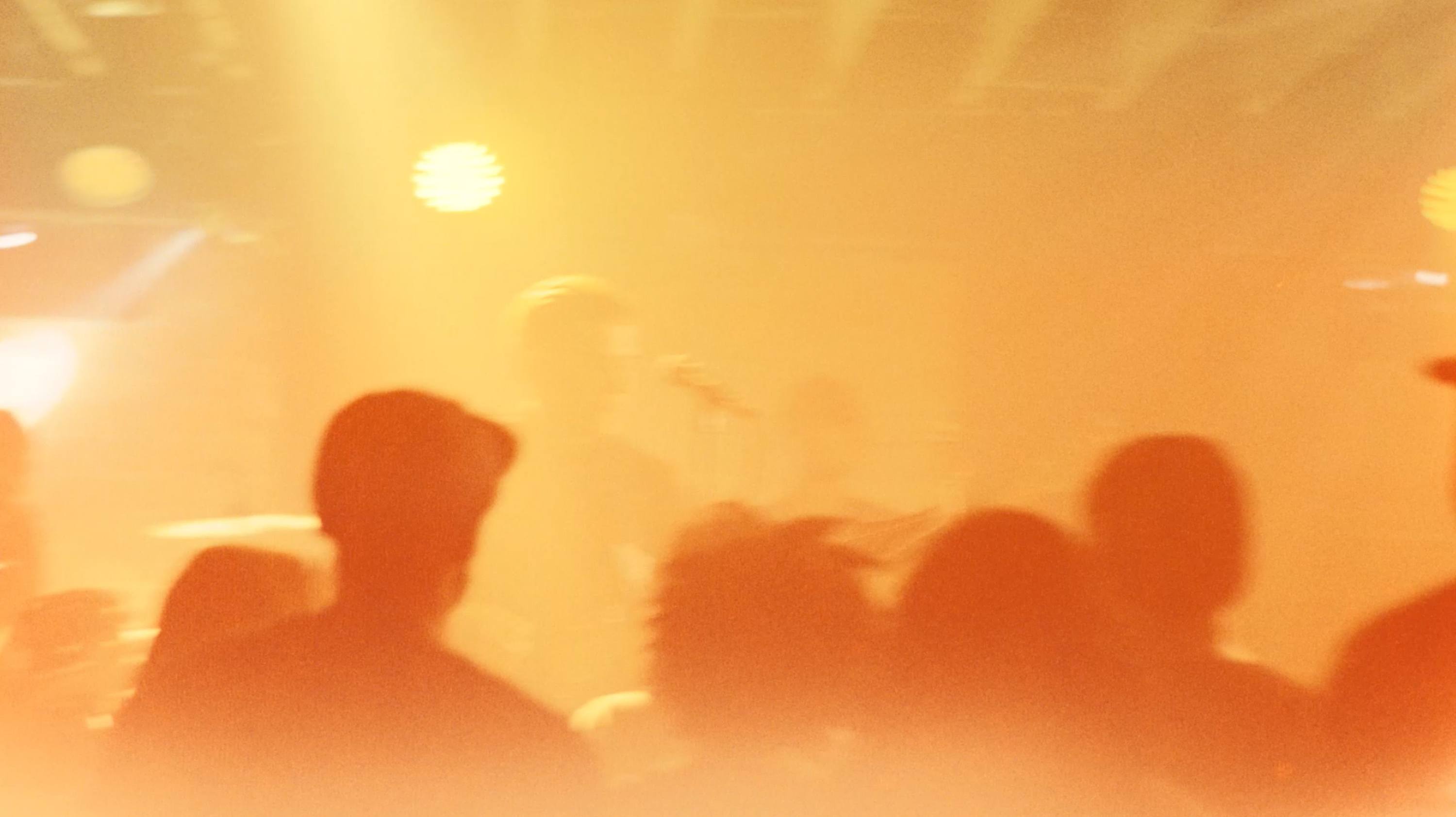 Silhouetted crowd under warm stage lighting at Saint Archer GOLD event
