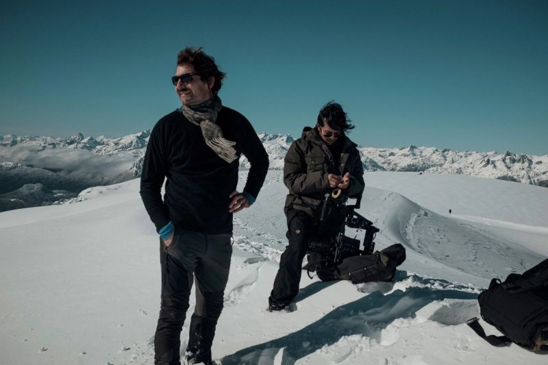 Cinematographer stands on a snowy mountain peak with a camera operator in Patagonia.
