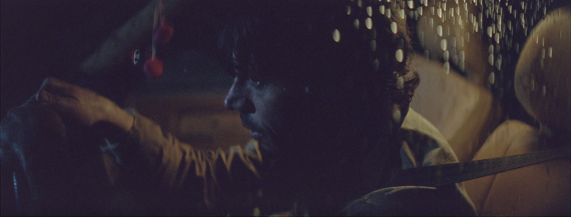 Cinematographer Ian Rigby captures moody film photography in a dimly lit car interior with raindrops on the window.