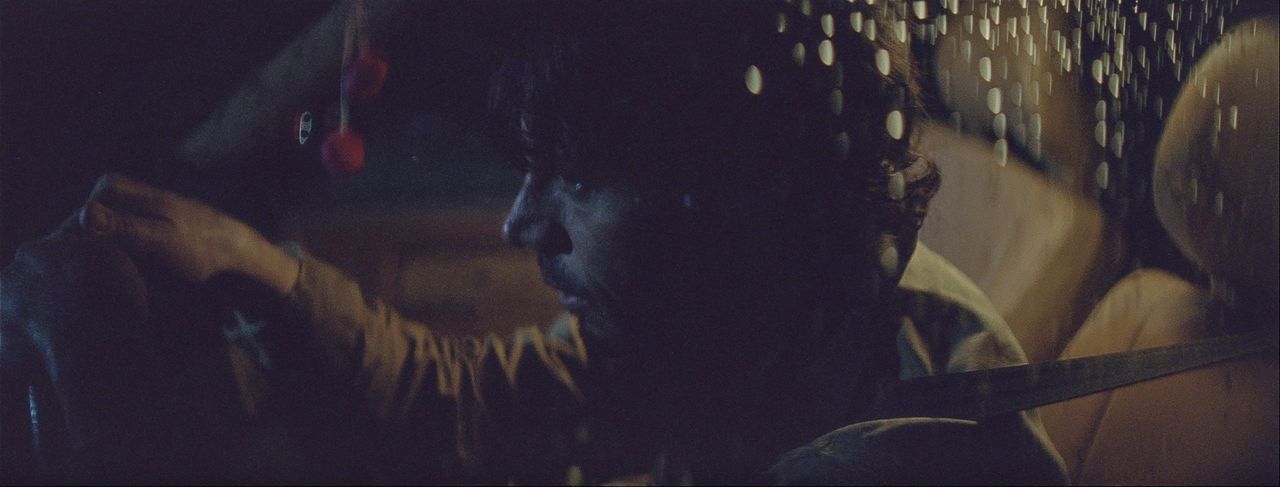 Cinematographer Ian Rigby captures moody film photography in a dimly lit car interior with raindrops on the window.