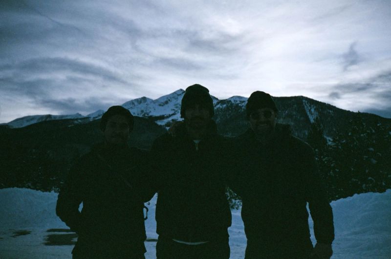 Three men silhouetted against snowy mountains and cloudy sky during a Toyota Olympics shoot.
