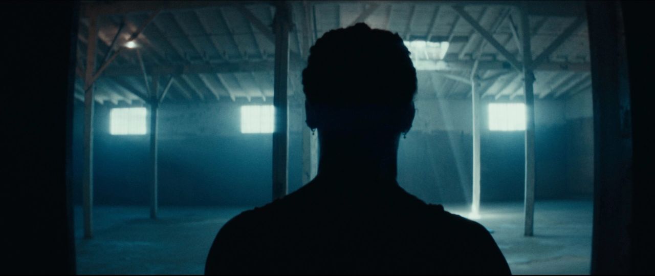 Helen Maroulis silhouette facing bright windows in a large warehouse interior.