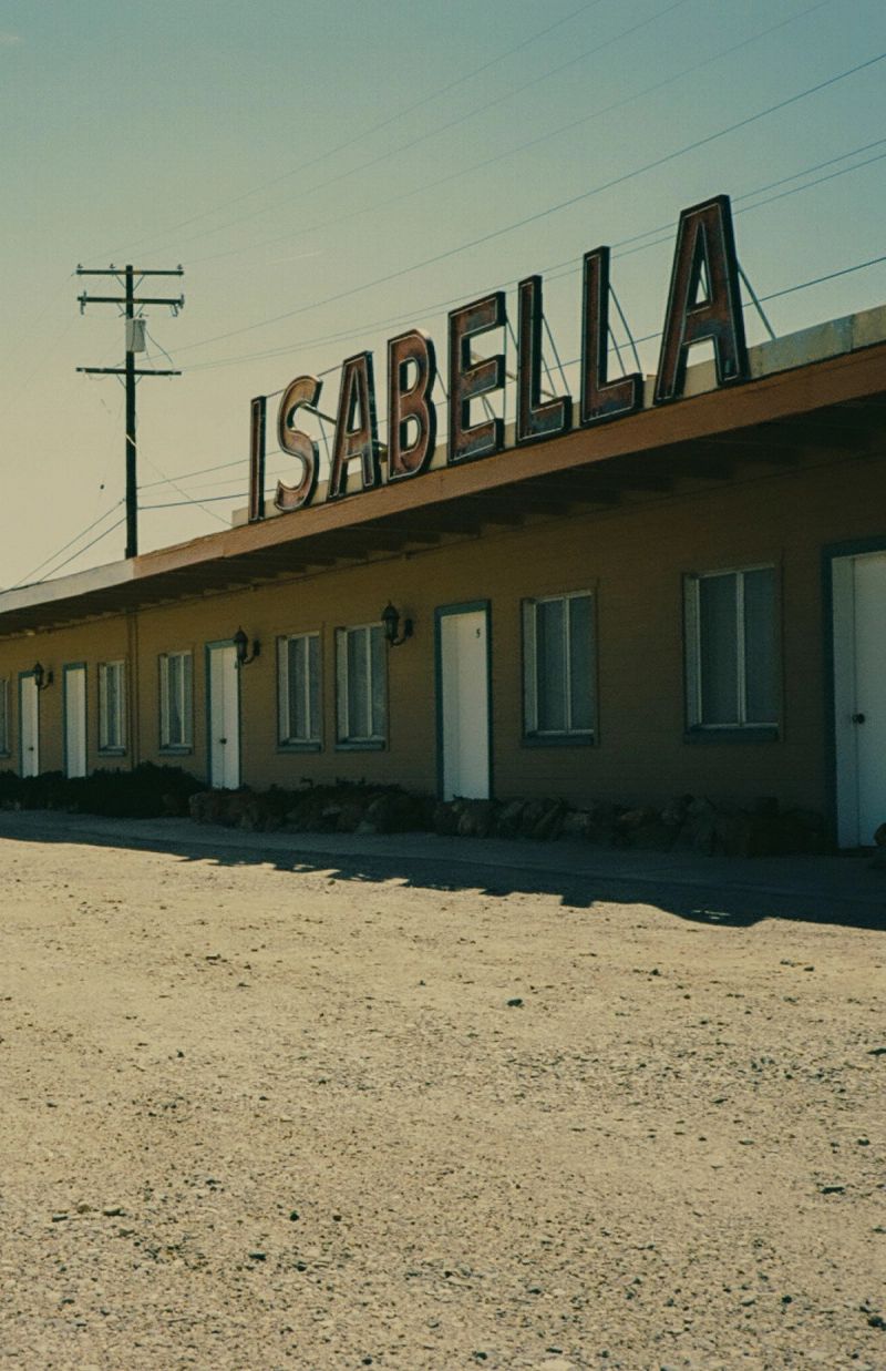 Isabella motel sign and rooms under bright sky, desert road foreground