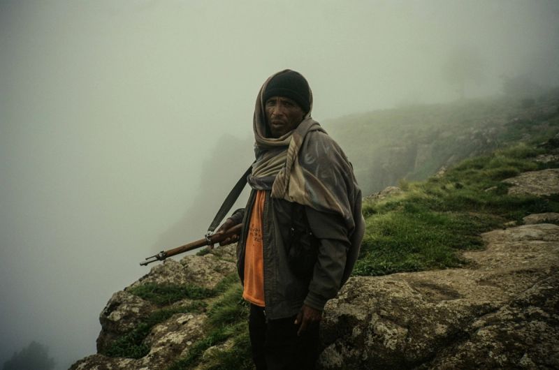 Man with rifle stands on misty ridge in Ethiopia for Lufthansa Airlines.