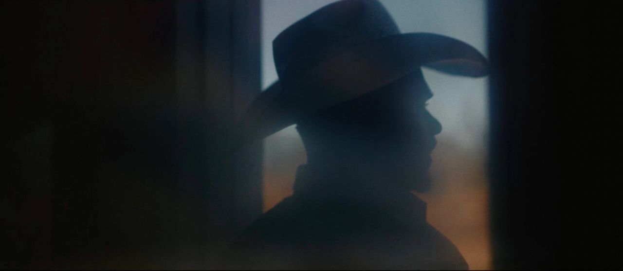 Silhouette of cowboy in hat against soft window light