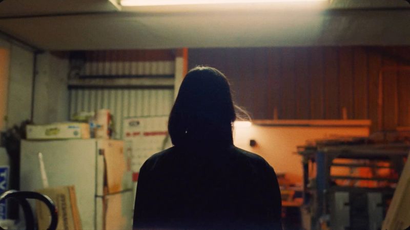 Silhouette of a person in a dimly lit garage with warm ambient lighting