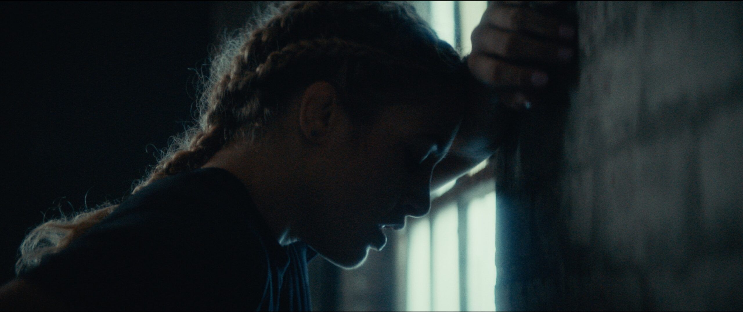 Profile of Olympic wrestler Helen Maroulis leaning against a wall, backlit by window bars in EastBay ConqHer.