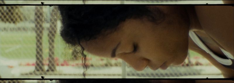 Profile of a female athlete with eyes closed, film photography style on a sports field.